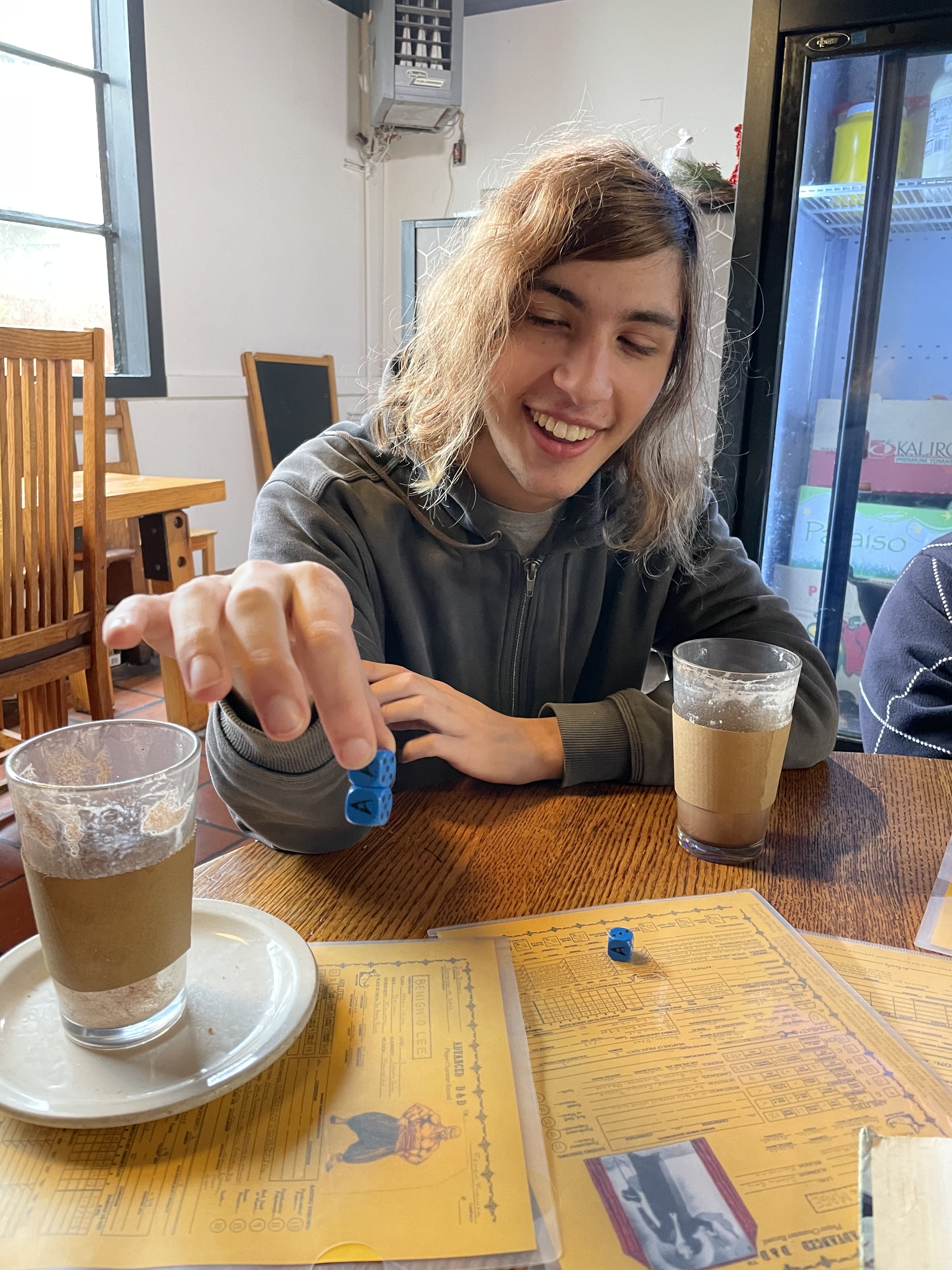 Alex holding magically fused dice over a collection of Dungeons and Dragons character sheets